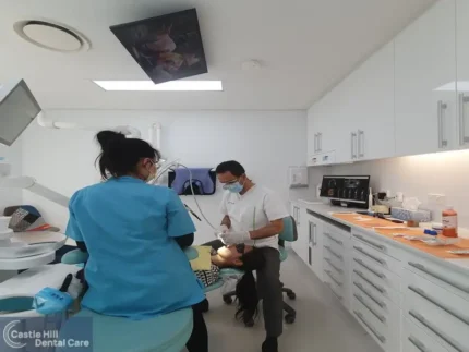 Picture of Dr. Jaafar of Castle Hill Dental Care performing dental procedure on a patient in blue dental chair.